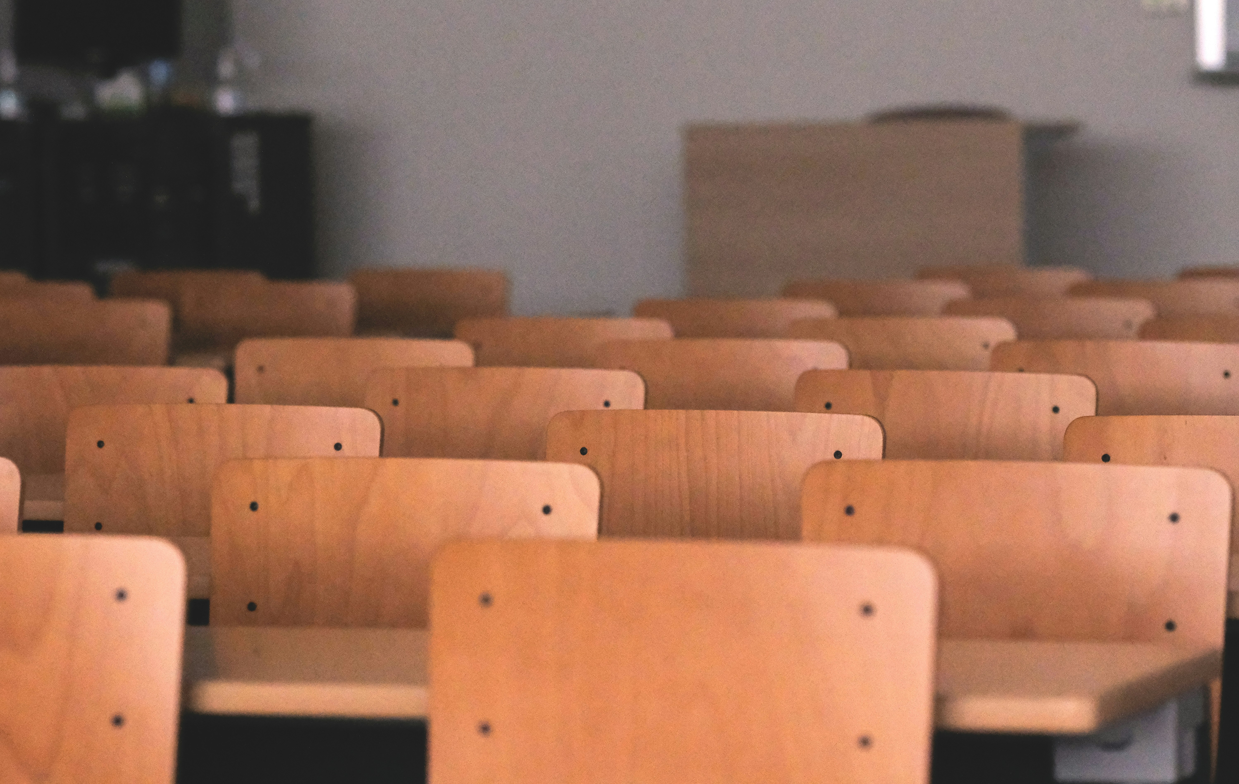 Photo of rows of school desk chairs in a classroom.